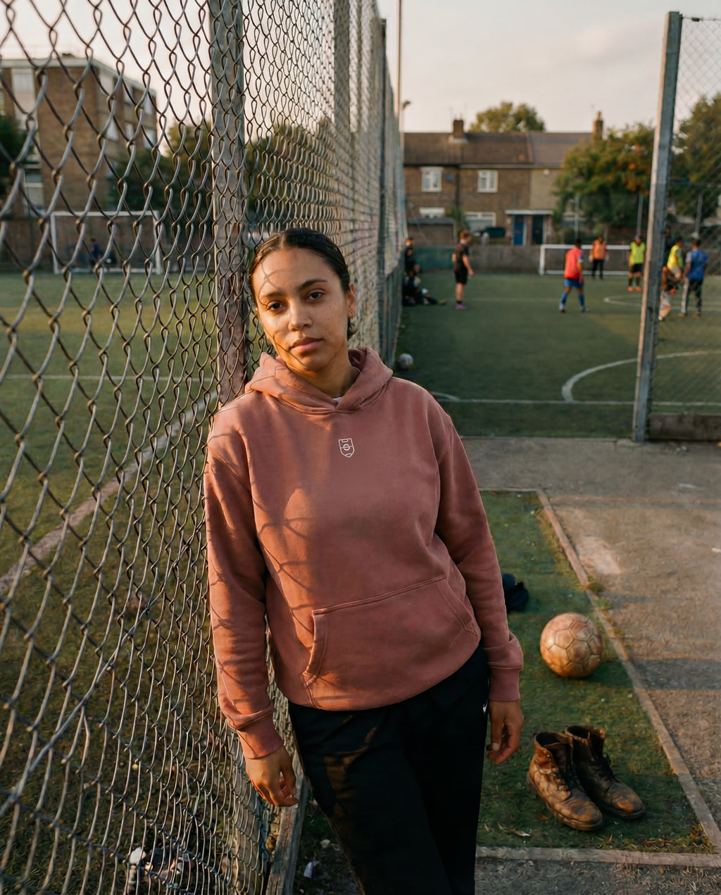 Person standing on a sports field with a soccer ball and goalposts in the background