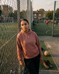 Person standing on a sports field with a soccer ball and goalposts in the background