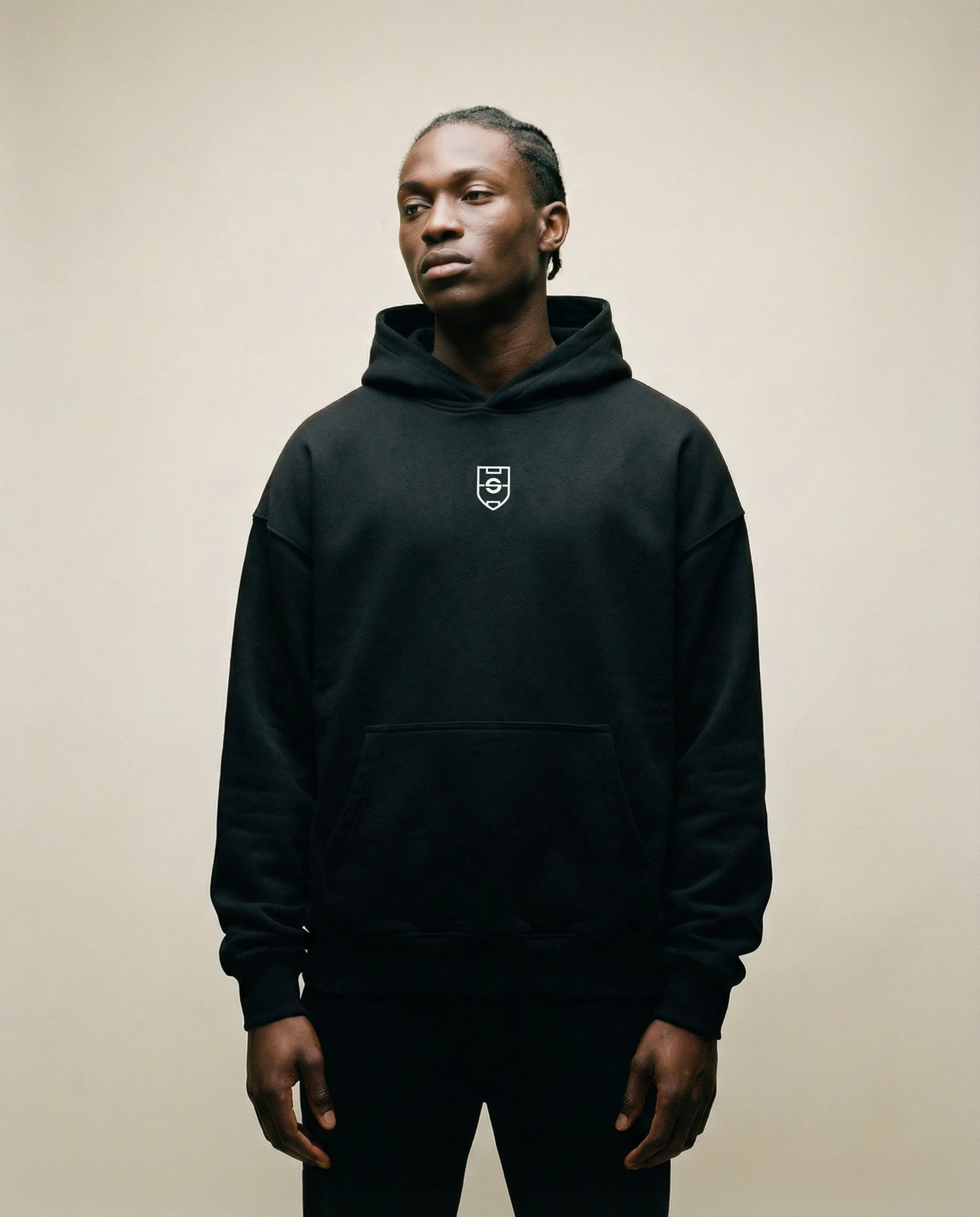 Person wearing a black hoodie with a logo on a beige background